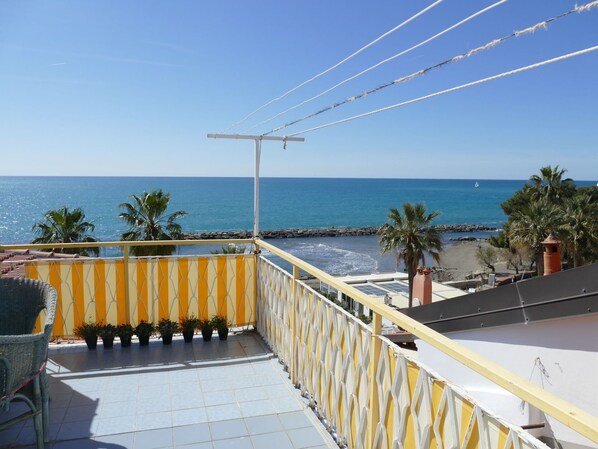Un balcon avec vue sur la mer, un sol carrelé et une balustrade.