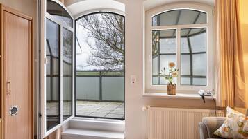 Ein Zimmer mit einer Schiebeglasdoor, einem Fenster mit Blick und einer Heizung, sowie ein Sofa mit Kissen.