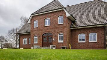Ein großes Backsteingebäude mit symmetrischer Fassade, zahlreichen Fenstern und einem zentralen Eingang.
