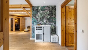 Un interior de madera con un armario blanco, un banco acolchado y una puerta que da a otra habitación.