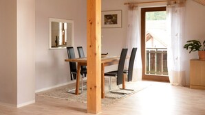 Un comedor con mesa y sillas de madera, una ventana con vistas y una planta en maceta.