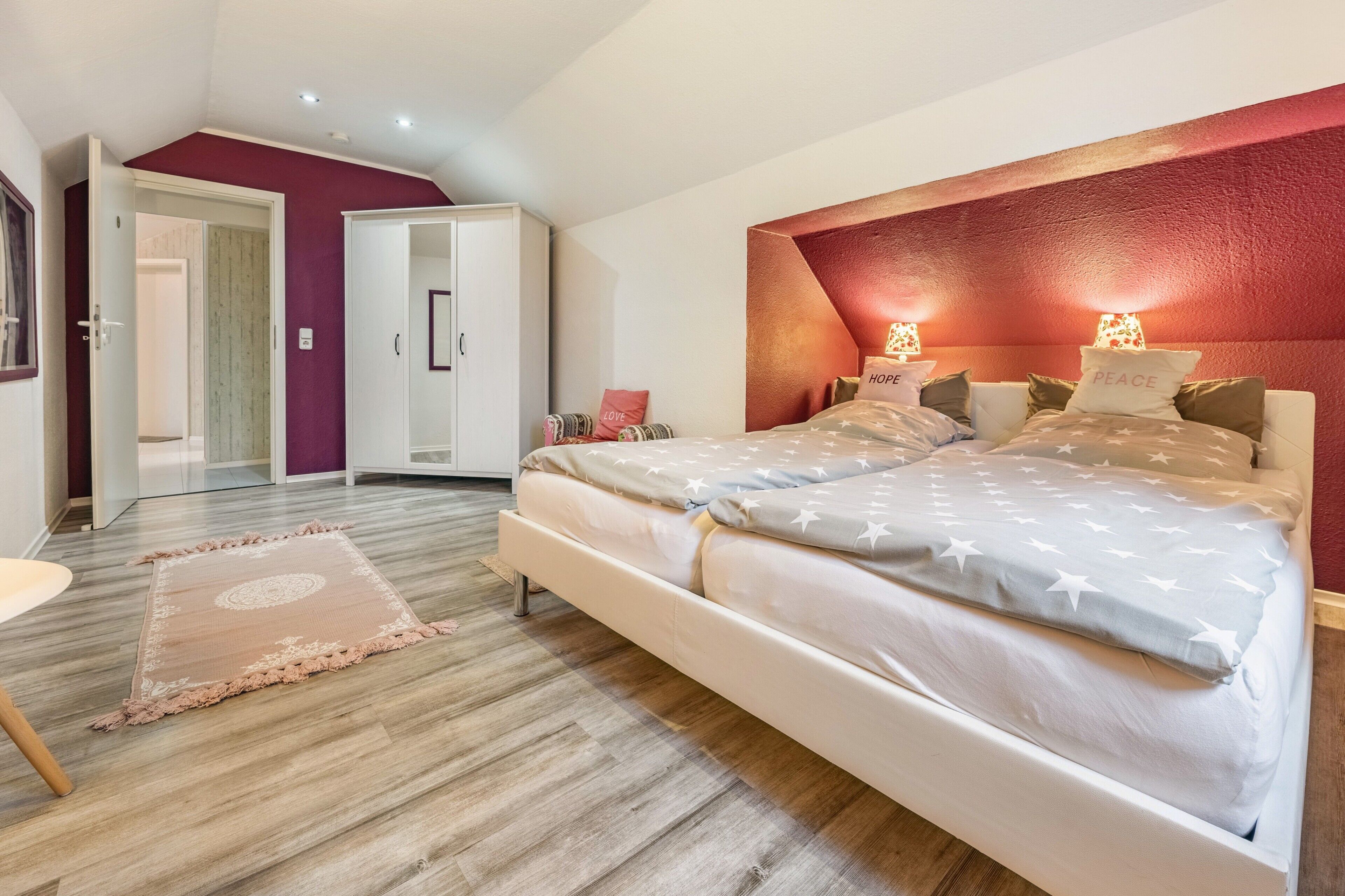 A bedroom with a bed, a wardrobe, a door, and a rug.