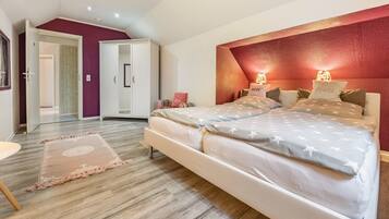 A bedroom with a bed, a wardrobe, a door, and a rug.
