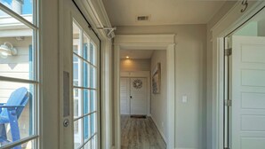 Un couloir avec un plancher en bois, une porte portant un numéro et une chaise bleue à l’extérieur.