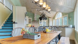 A kitchen with a wooden table, chairs, and a hanging pot rack. - Firepit, Cozy Farmhouse & Adventure Nearby | Catskill Park Farm by AvantStay (Prattsville)