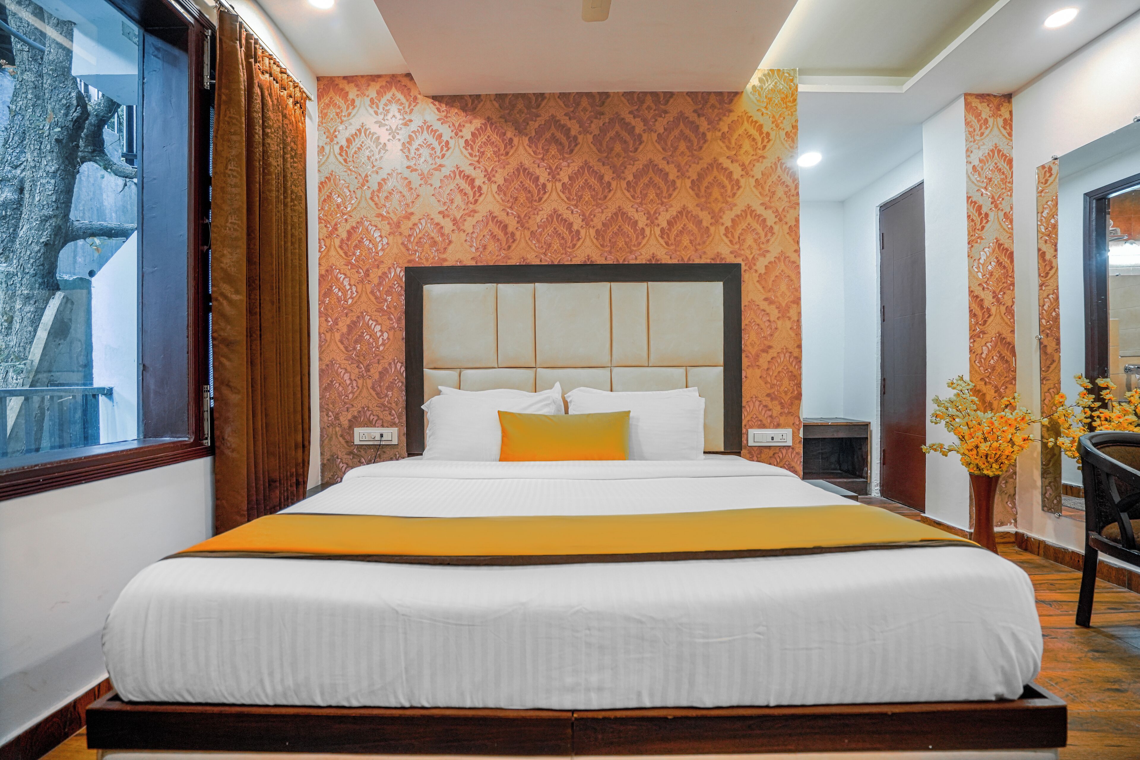 A large bed with a headboard, white bedding, and a yellow accent.