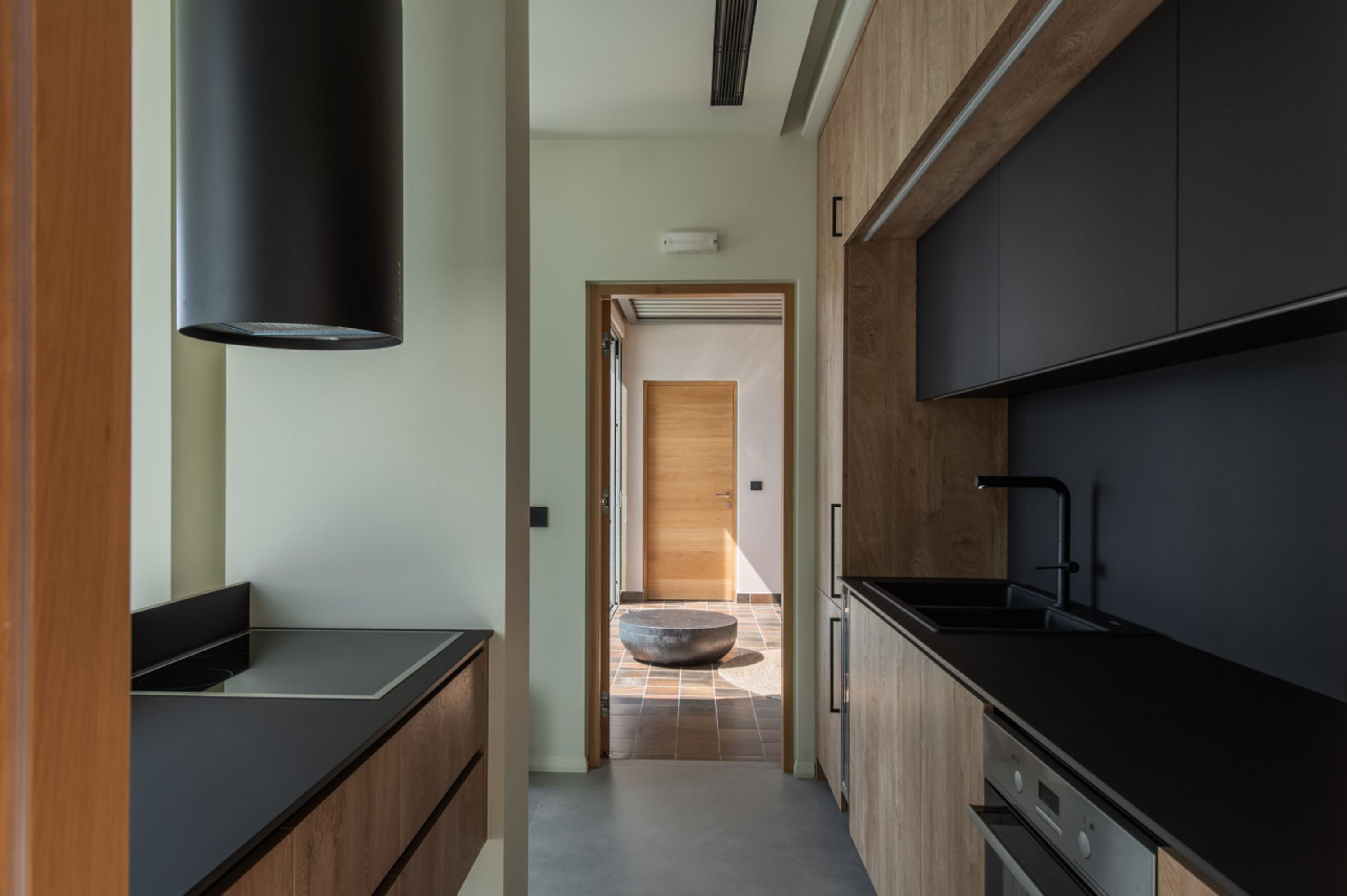 Una cocina moderna con armarios oscuros, una encimera negra y un horno empotrado.
