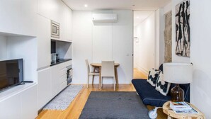 Ein kompakter Wohnbereich mit Küchenzeile, Essbereich und Sitzecke mit Sofa und Lampe.
