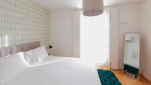 A bedroom with a large bed, a mirror, and a geometric-patterned wall.