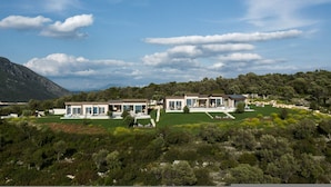 A modern villa with multiple rooms, a well-maintained lawn, and a mountainous backdrop. - EGO Villas in Vasiliki (Lefkada)