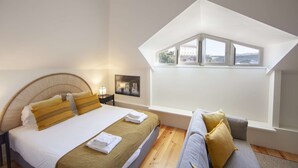 Un dormitorio con cama, sofá, ventana y un cuadro en la pared.