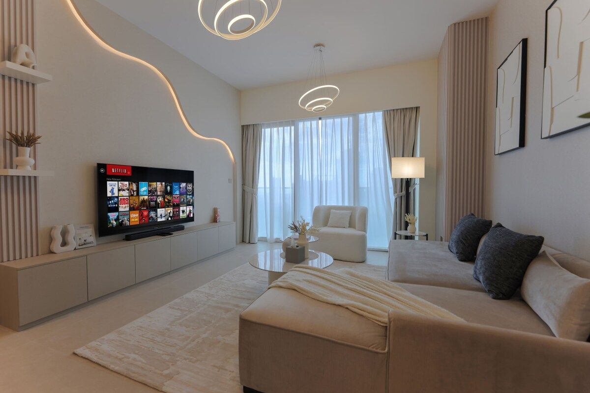 A modern living room with a flat-screen TV, a sofa, a coffee table, and a lamp.