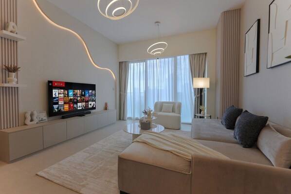 A modern living room with a flat-screen TV, a sofa, a coffee table, and a lamp.