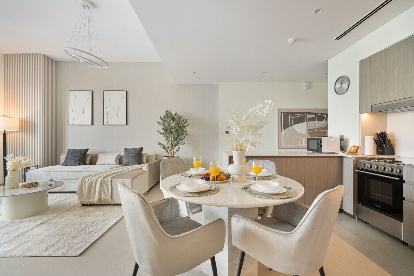 A modern, well-lit living room with a dining area, a kitchen, and a bedroom.