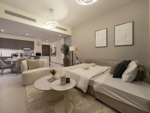 A modern hotel room with a sofa, a bed, a small table, and a dining area in the background. - New 1BR | Burj Khalifa Infinity Pool | Dubai Mall (Dubai)