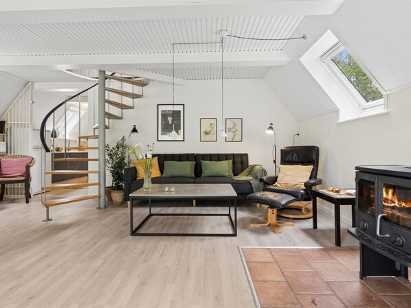 Un loft moderne doté d’un escalier à volutes, d’une cheminée et d’un coin salon confortable.