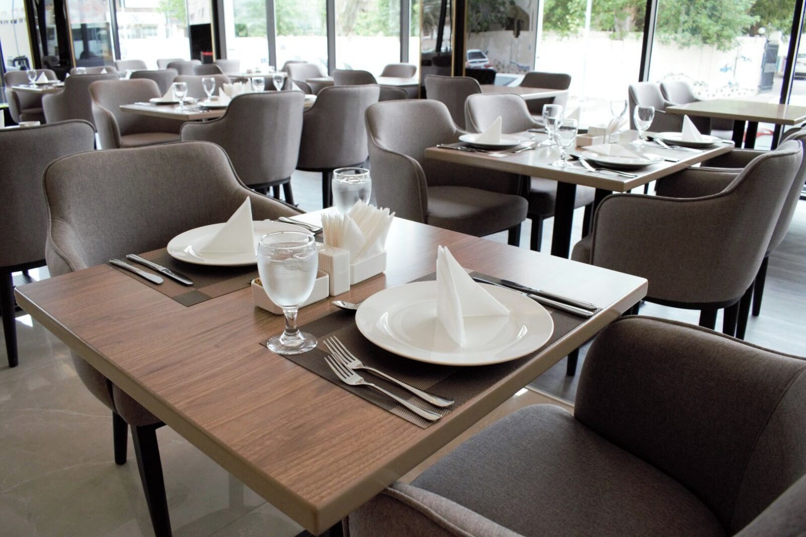 Ein Restaurant mit mehreren Tischen, jeweils gedeckt mit Geschirr, Besteck und Gläsern.