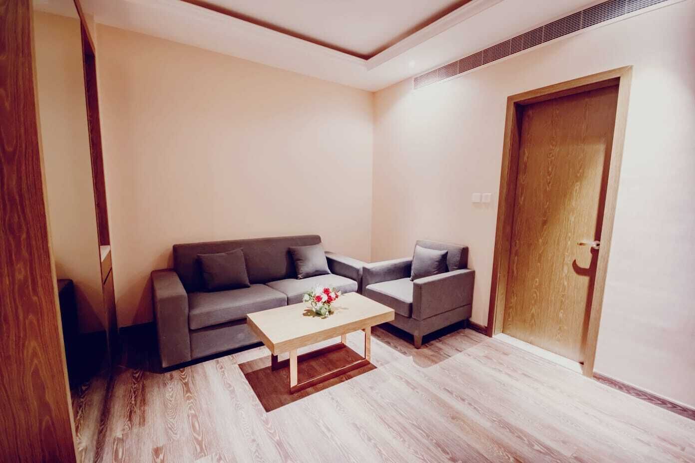 Una sala de estar moderna con un sofá gris, un sillón gris más pequeño y una mesa de centro de madera.