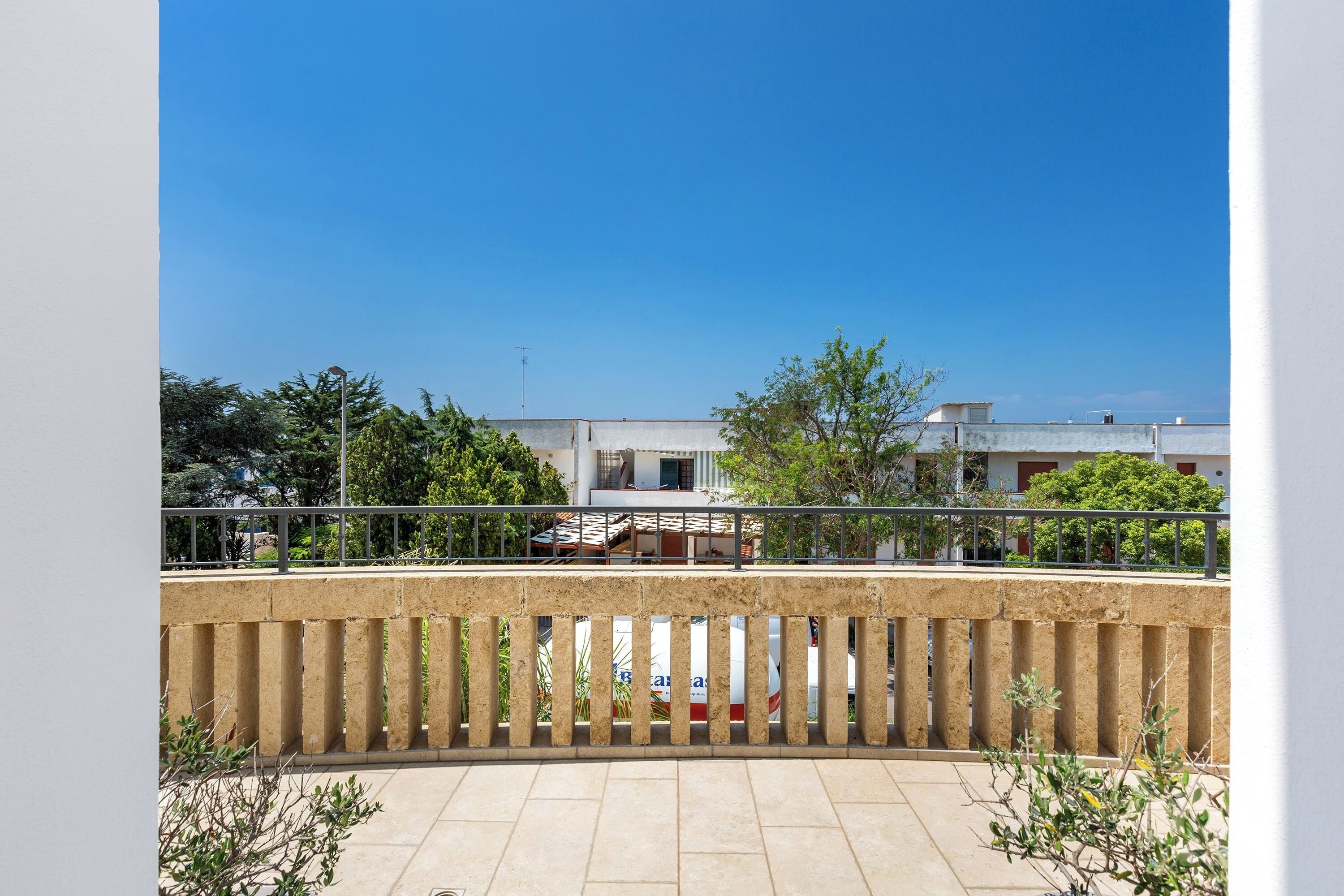 A balcony with a view of buildings and trees.