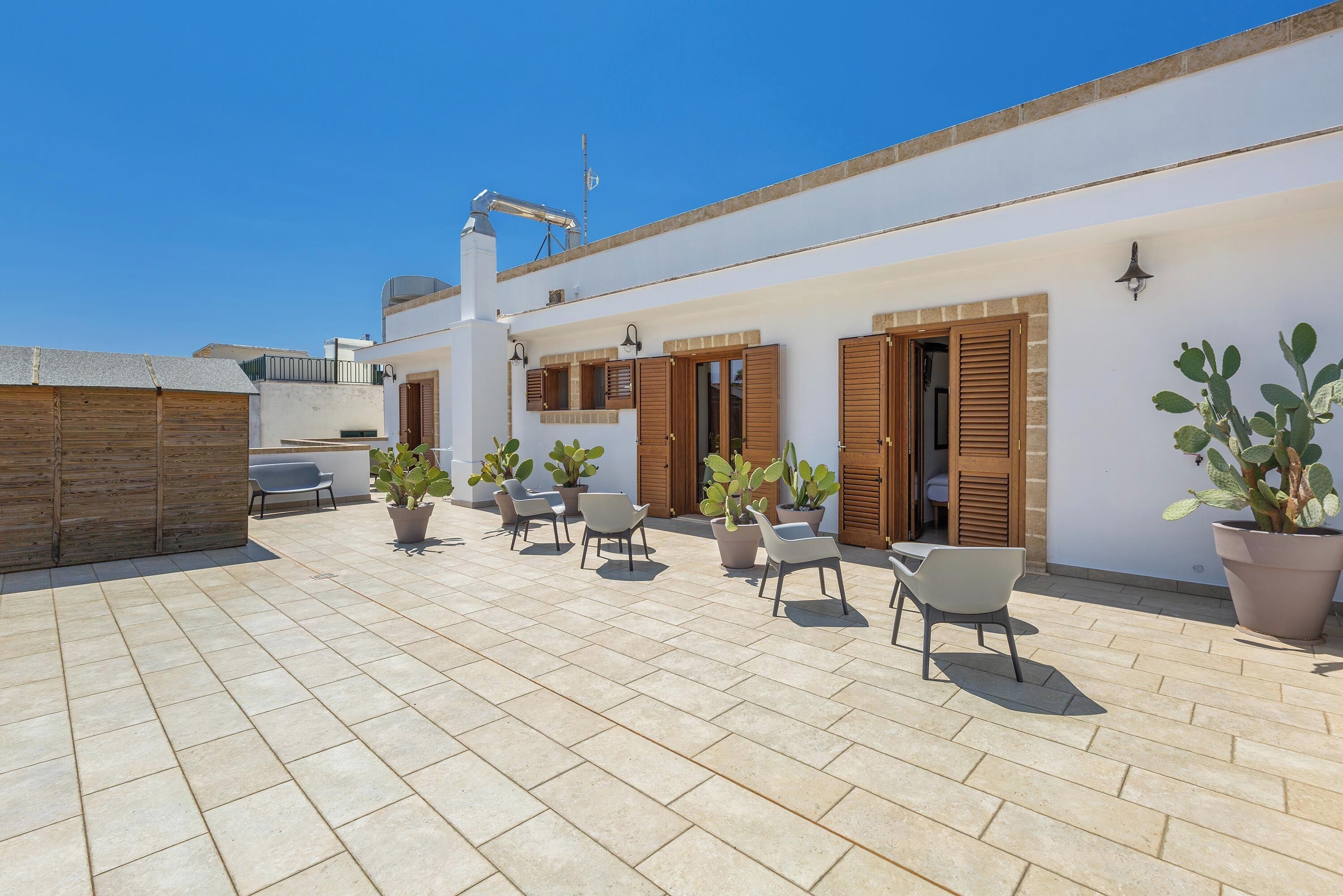 A rooftop patio with tiled flooring, potted plants, and outdoor seating.