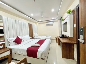 A hotel room with two beds, a TV, a desk, and an air conditioning unit. - Hotel SRK - near Temple  (Varanasi)