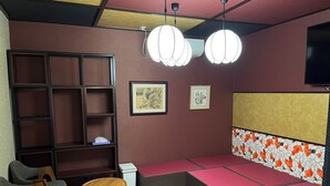 Quarto com área de estar, estante de livros e duas imagens emolduradas na parede.