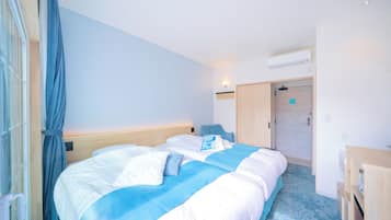 A hotel room with a bed, a desk, a chair, a wardrobe, and a bathroom door.