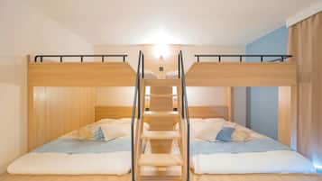 Habitación con literas, una escalera central, paredes de madera e interruptor de luz en la pared.