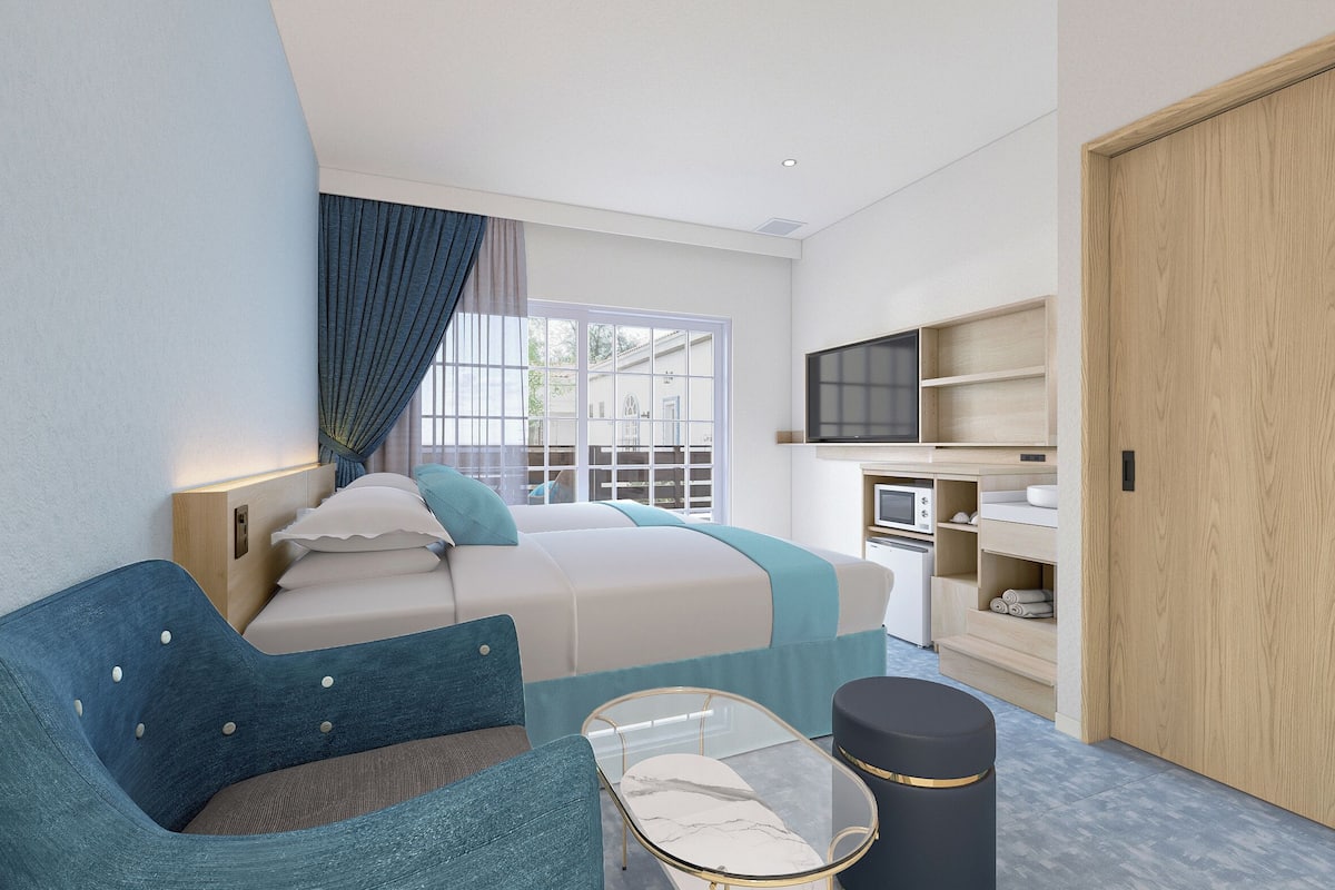 Une chambre d’hôtel moderne équipée d’un lit, d’un canapé, d’une table basse en verre, d’une télévision et d’une kitchenette.