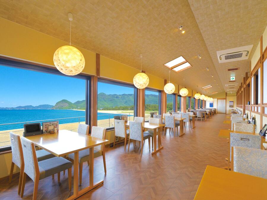 Un restaurant doté de grandes fenêtres offrant une vue sur la mer et les collines.