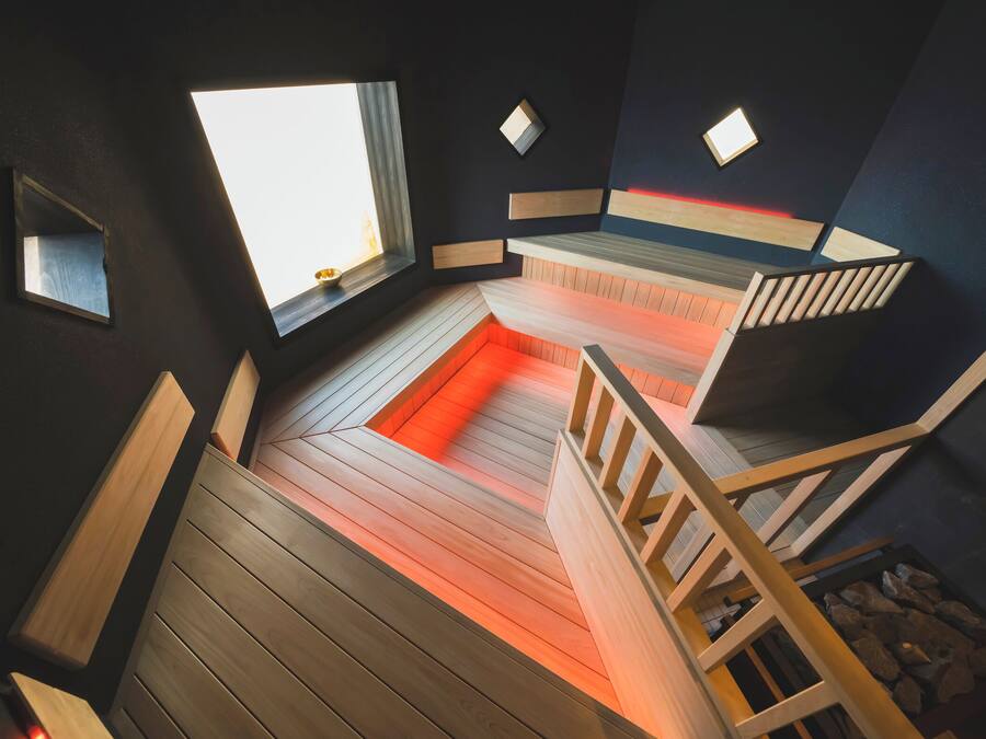 A modern interior with a wooden floor, a staircase, and a window providing natural light.