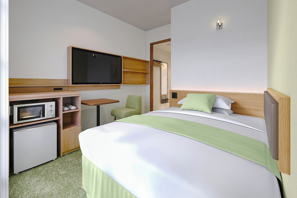 Une chambre d’hôtel équipée d’un lit, d’un téléviseur fixé au mur, d’un four à micro-ondes et d’une petite table.