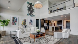 A spacious living area with a white sofa, a coffee table, and artwork on the walls. - Entire Top Floor Penthouse Loft, sleeps 20 (Atlanta)
