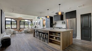 A modern kitchen with a central island, bar stools, and a large window overlooking a patio area. - Entire Top Floor Penthouse Loft, sleeps 20 (Atlanta)
