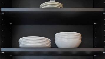 Una columna de prestatges negre amb plats i tasses blancs.