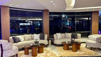 A modern living room with a sofa set, coffee tables, and a view of the city at night.
