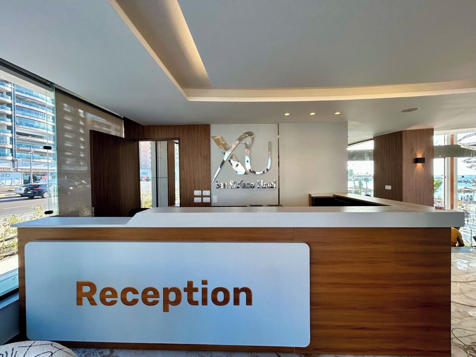 Ett välkomnande område med modern design, med en receptionsdisk märkt med "Reception" och en väggmonterad skylt med texten "San Seffas Hotel".
