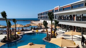 Un hotel moderno con piscina, sillas de descanso y sombrillas.