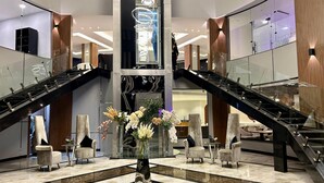 Un vestíbulo moderno con una mesa de cristal central, dos escaleras y un candelabro espiral decorativo.
