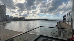 Un balcón con vista a la playa y al mar bajo un cielo nublado.