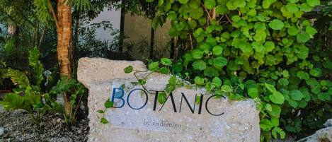 A stone sign with the word "BOTANIC" and the name "by endemica" in a garden setting.