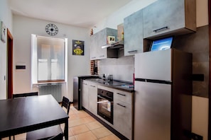 A modern kitchen with a refrigerator, oven, and a clock on the wall. - The pleasure of feeling at home (Perugia)