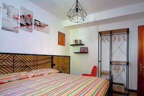 A bedroom with a bed, a red chair, a wardrobe, and wall art. - The pleasure of feeling at home (Perugia)