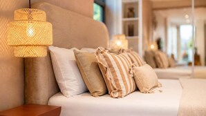 A modern hotel room with a sofa bed, a woven lamp, and a wooden side table.