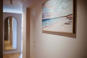 Ein Flur mit einem gerahmten Gemälde einer Strandansicht an der Wand.