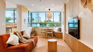 A modern living room with a sofa, a round coffee table, and a TV mounted on the wall.