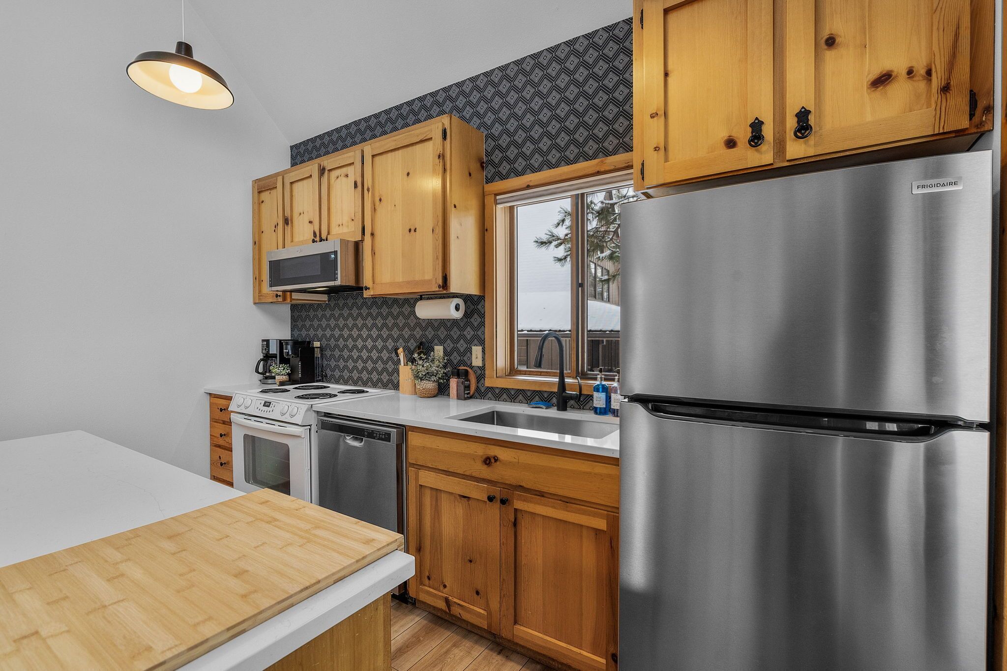 Een moderne keuken met houten kastjes, roestvrijstalen apparatuur en een grote koelkast.