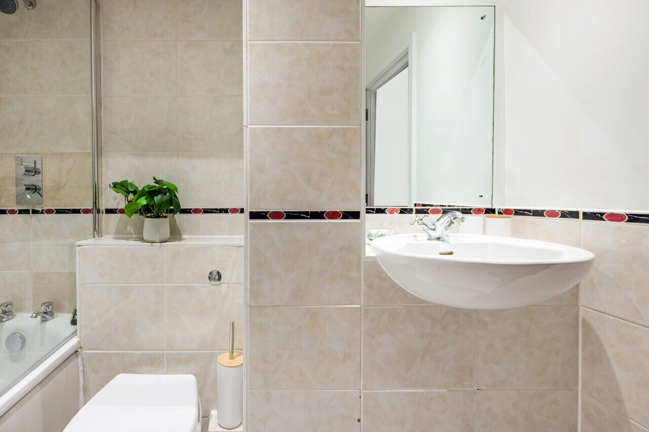 A bathroom with a bathtub, toilet, sink, and a mirror.