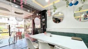 A modern dining area with a white table, white chairs, and a green sofa. - Hotel Rudra - near Ghats and Temple (Varanasi)