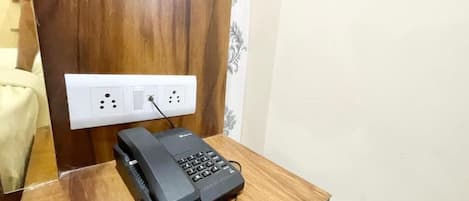 Escritorio de madera con un teléfono y un enchufe.